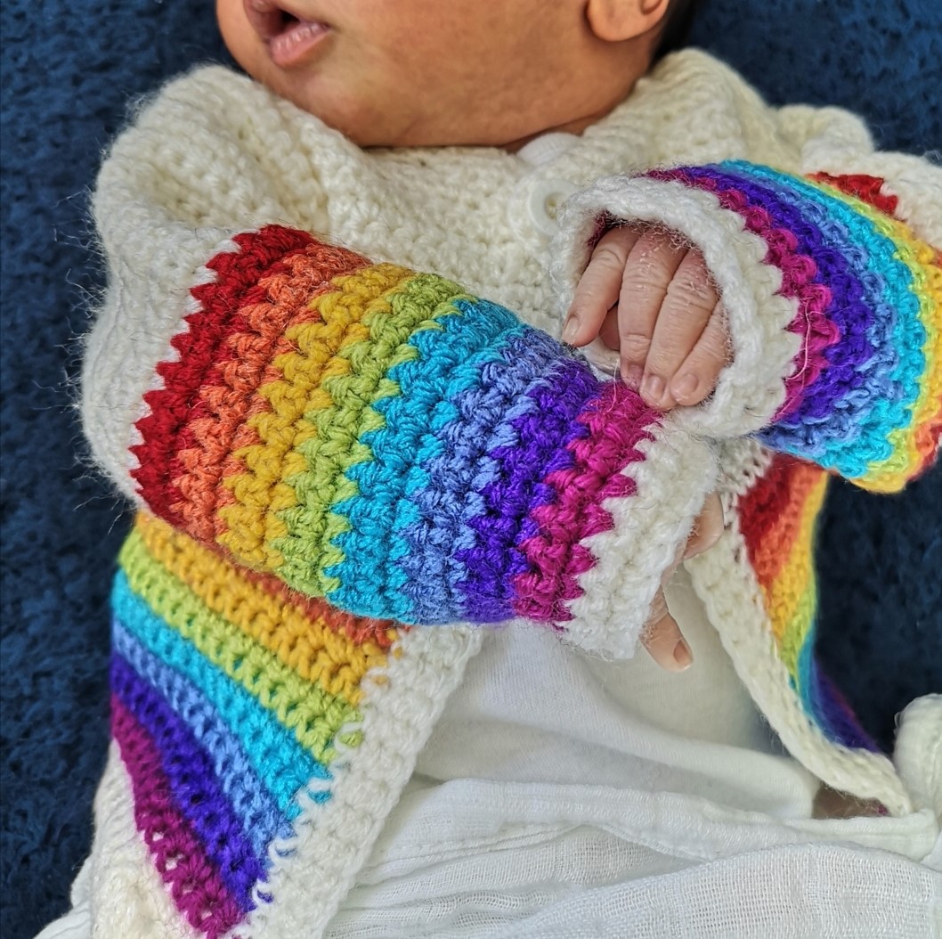 A baby in a rainbow cardigan