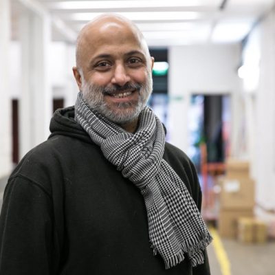 Rajpal Pardesi. A smiling man wears a black hoodie and a grey scarf
