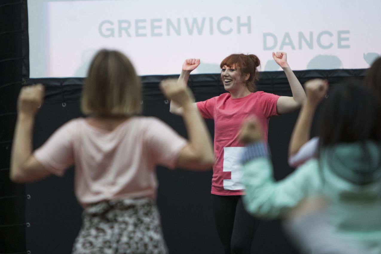 A woman teaching dance in front of a Greenwich Dance logo