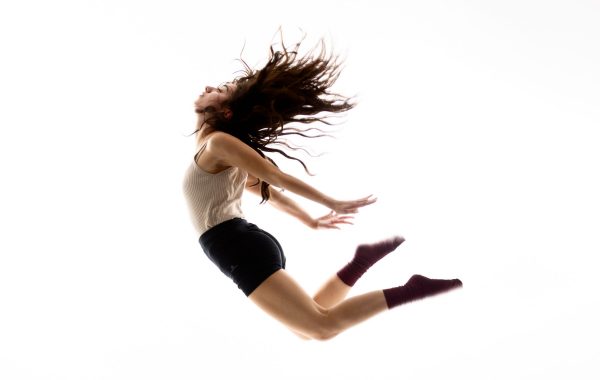 A woman jumping with arms pushed back and hair splayed out