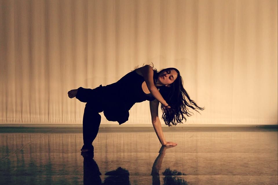 A woman dancing with one hand and one foot touching the floor