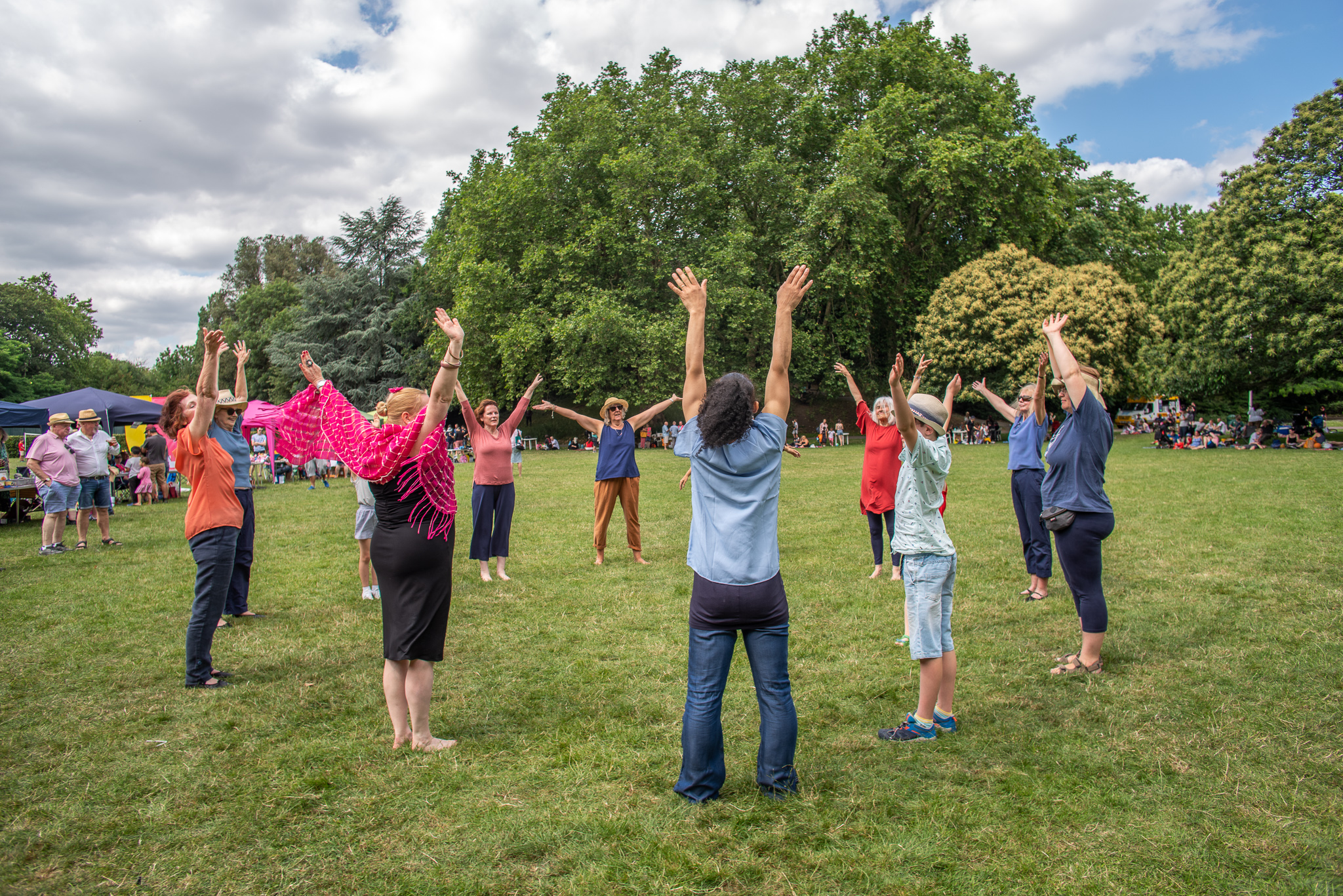 Stride on Time. A group of people standing in a circle outside, with arms stretched upwards