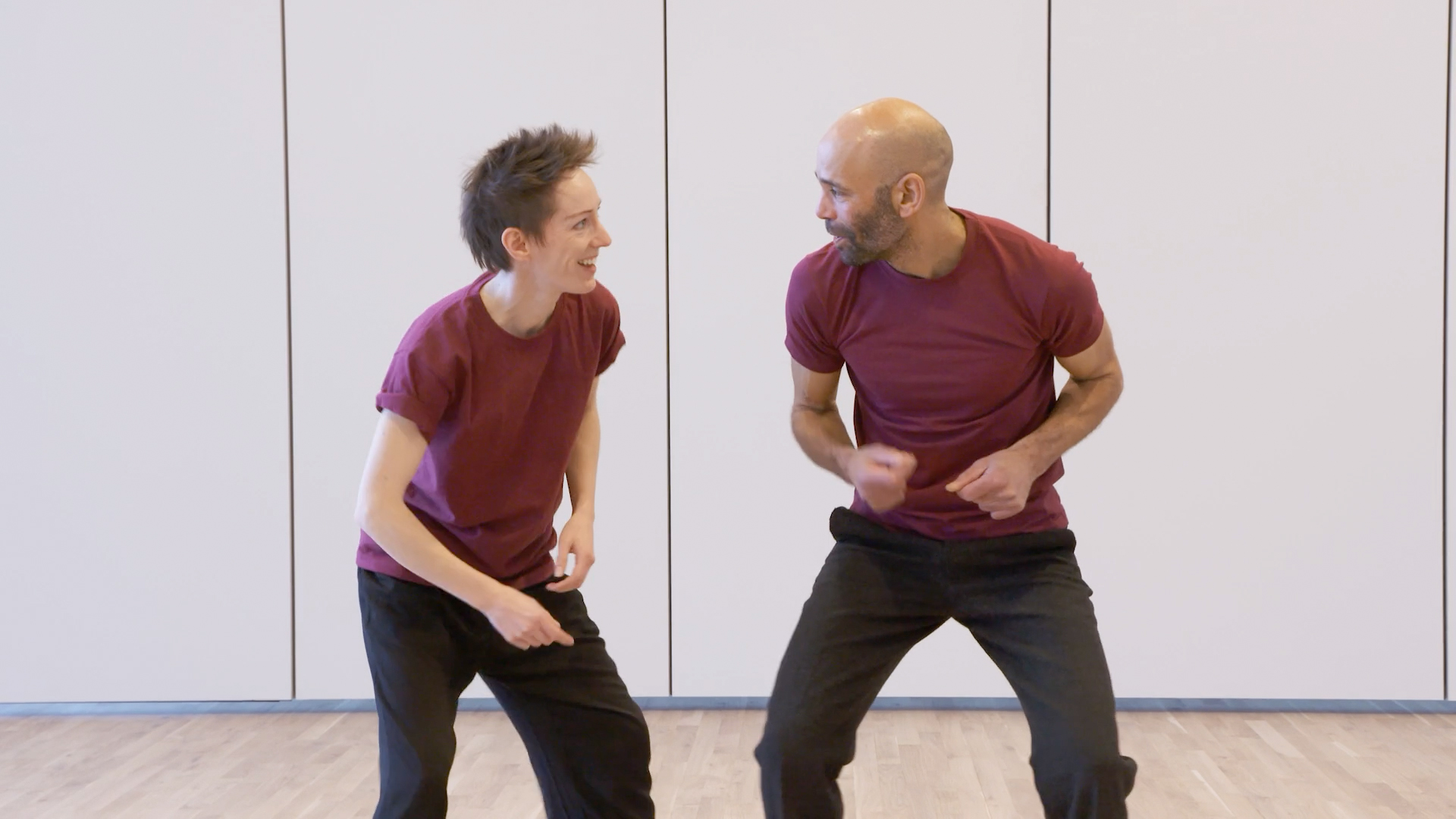 Lindy Hop tutorial 1. Dancers Wendy, a white woman with spiky brown hair, and Temujin, a man with brown skin and closely shaved head, click their fingers
