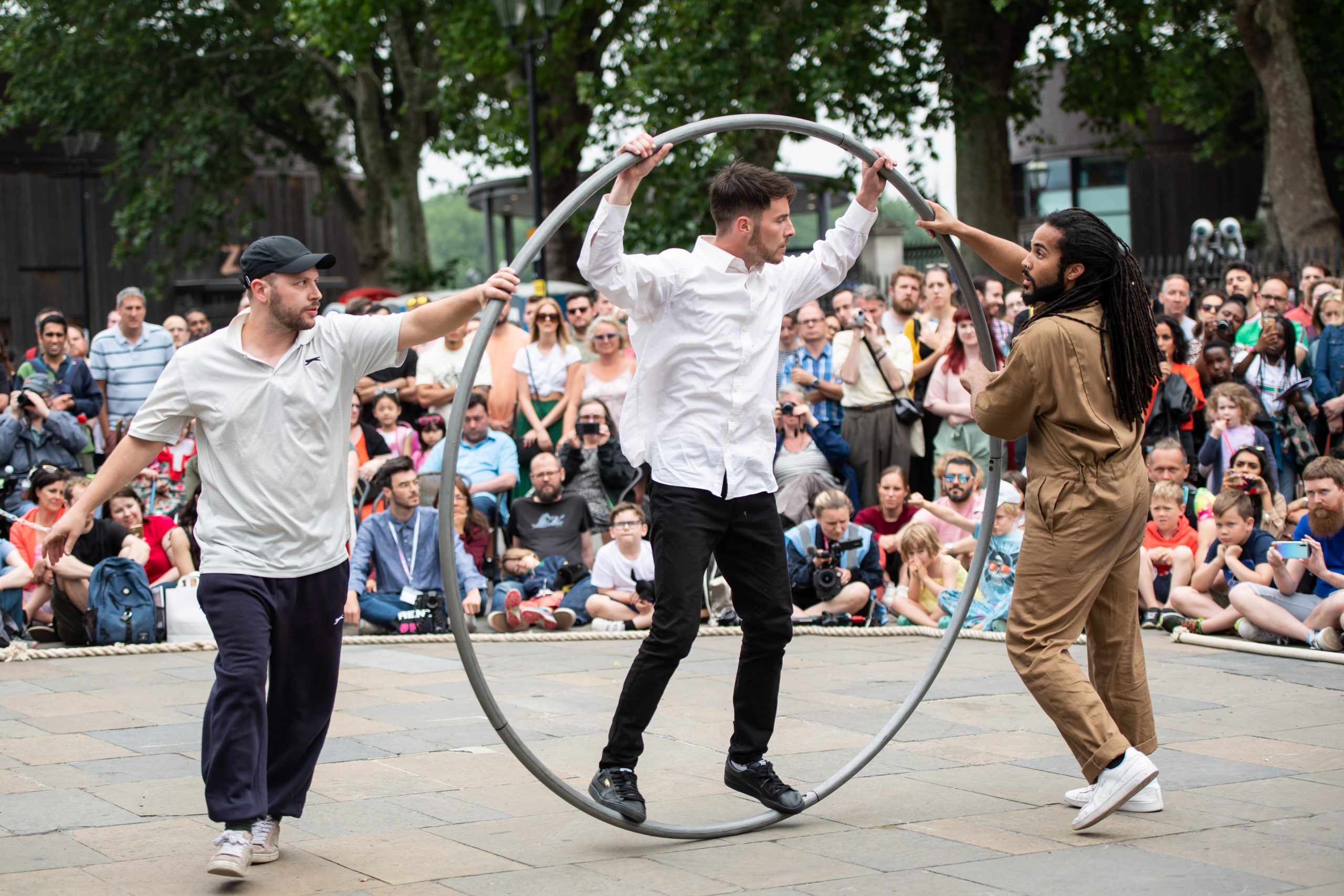 Simple Cypher. Two performers hold a large hoop or cyr wheel with one performer balanced inside