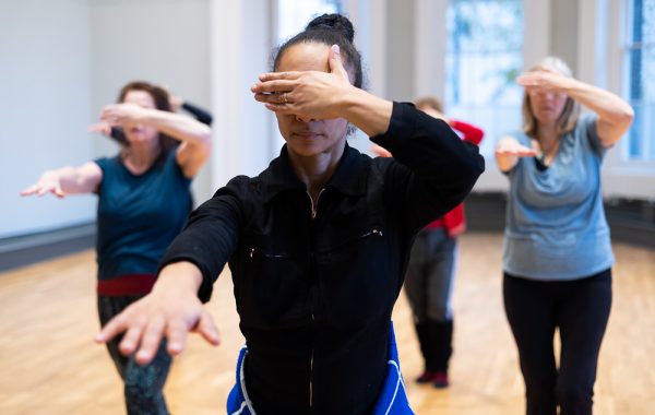 Navigating the past year. Dancers in the studio cover their eyes with one hand and reach out with the other.